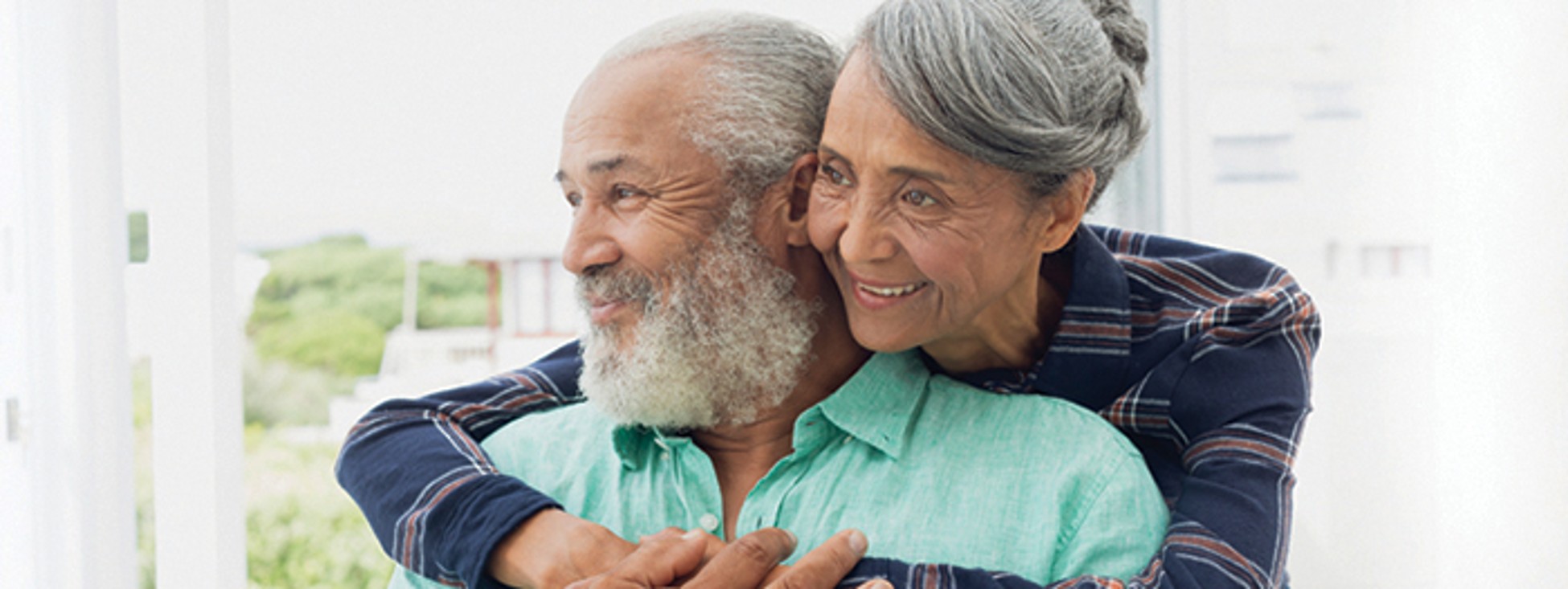 Smiling older couple embracing, looking out a window together