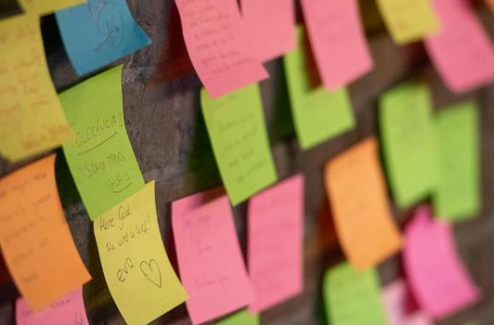 Wall covered in pink, green, orange, and yellow sticky notes